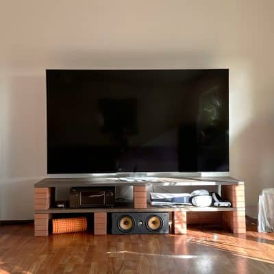 Ein großer Fernseher steht auf einer niedrigen Kommode mit offenen Fächern.