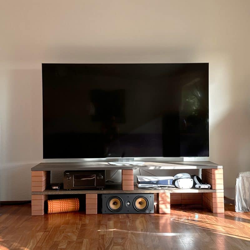 Ein großer Fernseher steht auf einer niedrigen Kommode mit offenen Fächern.