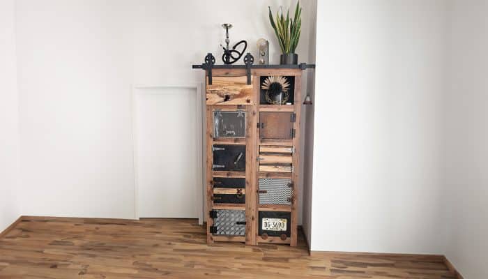 Ein Holzregal zeigt unterschiedliche Metallplatten und dekorative Gegenstände.