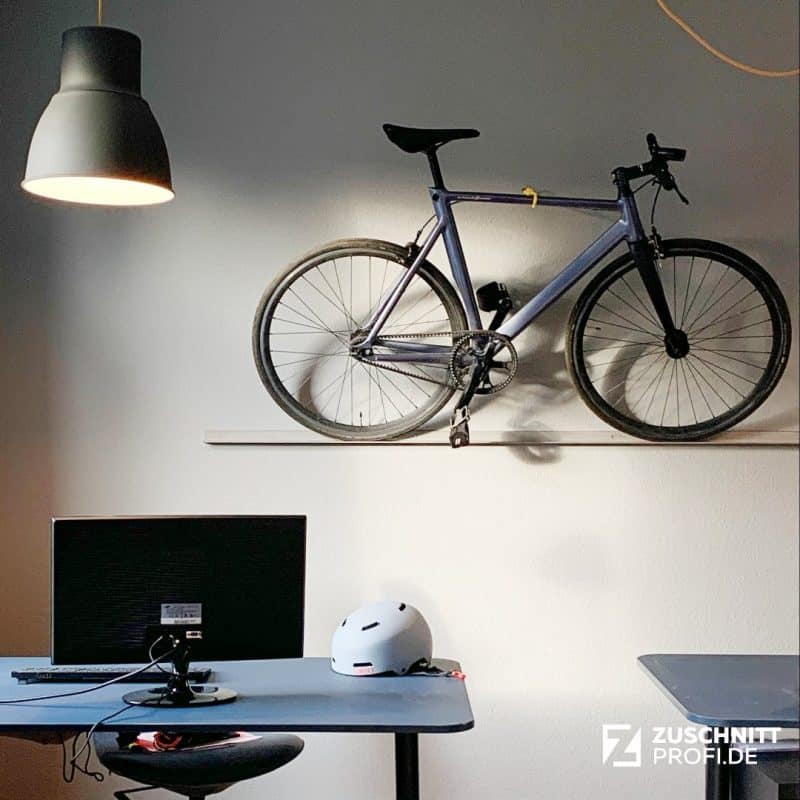 Stahlprofil dient als minimalistischer Fahrradhalter an der Wand.