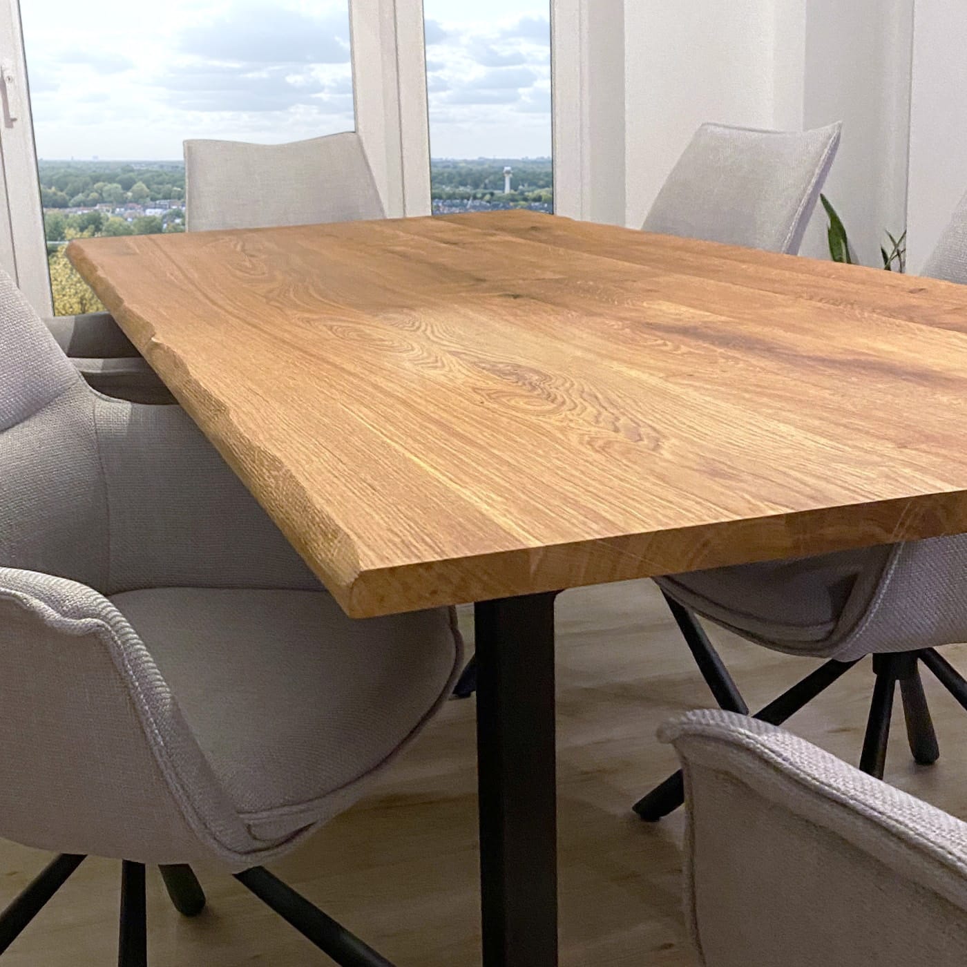 Ein großer Tisch aus Massivholz steht in einem hellen, modernen Essbereich.