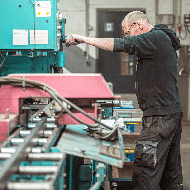 Ein Mitarbeiter bedient eine Maschine zur Metallbearbeitung in der Werkhalle.