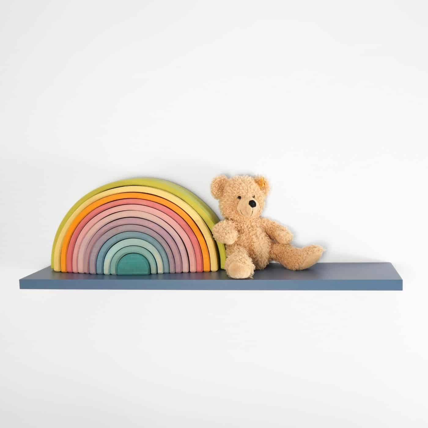 Blaues Dekor-Wandregal mit buntem Regenbogen und Teddybär als Dekoration.
