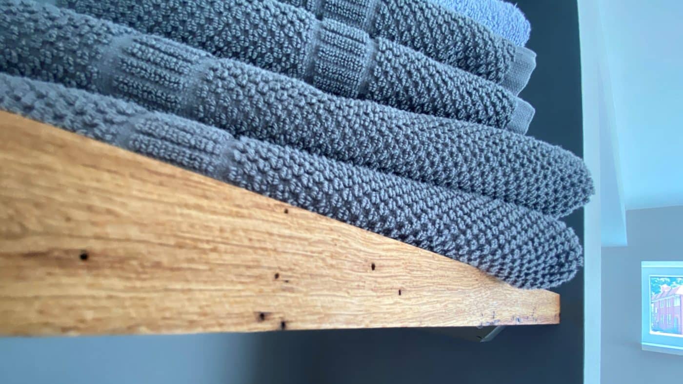 Aufeinandergelegte, graue Strickhandtücher liegen ordentlich auf einer Holzfläche.
