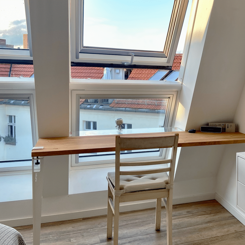 Eine Holzarbeitsplatte liegt passgenau auf einem Tisch am Fenster.