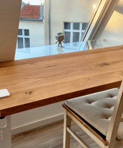 Eine Holzarbeitsplatte liegt passgenau auf einem Tisch am Fenster.