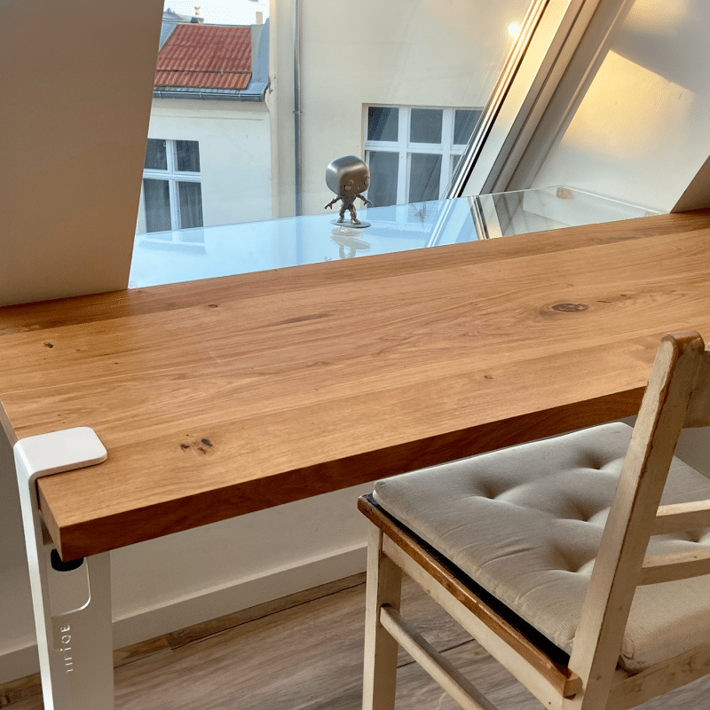 Eine Holzarbeitsplatte liegt passgenau auf einem Tisch am Fenster.
