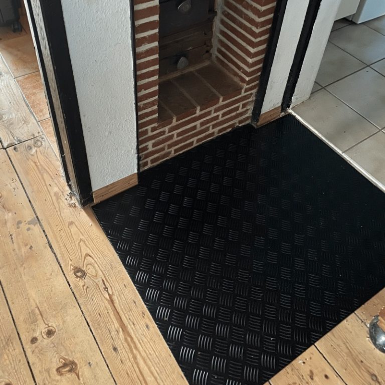 Schwarzes Riffelblech als Verkleidung für einen Kamin, hitzebeständig, robust und modern verarbeitet.