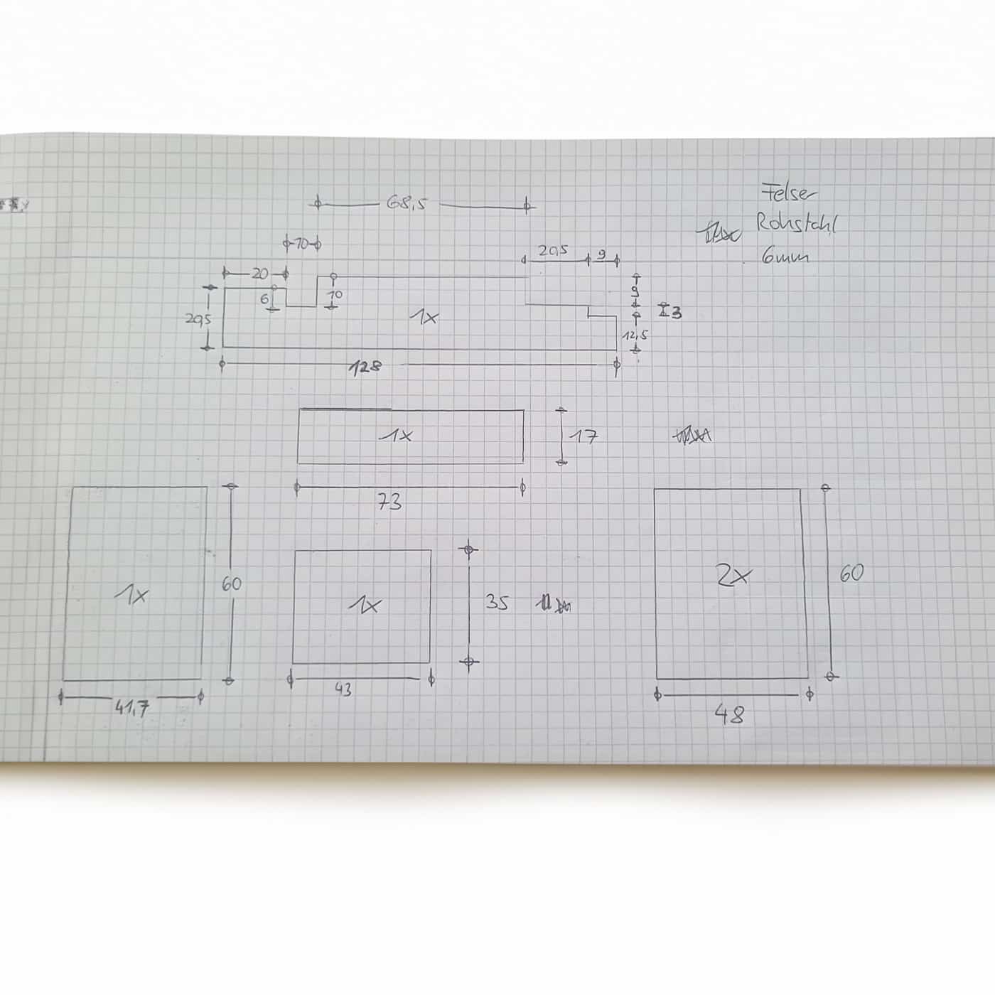 Eine technische Zeichnung zeigt Maße und Skizzen auf kariertem Papier.