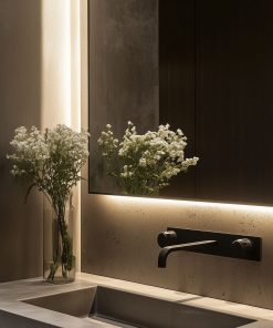 Beleuchteter Spiegel über Waschbecken mit Glasvase und weißen Blumen.
