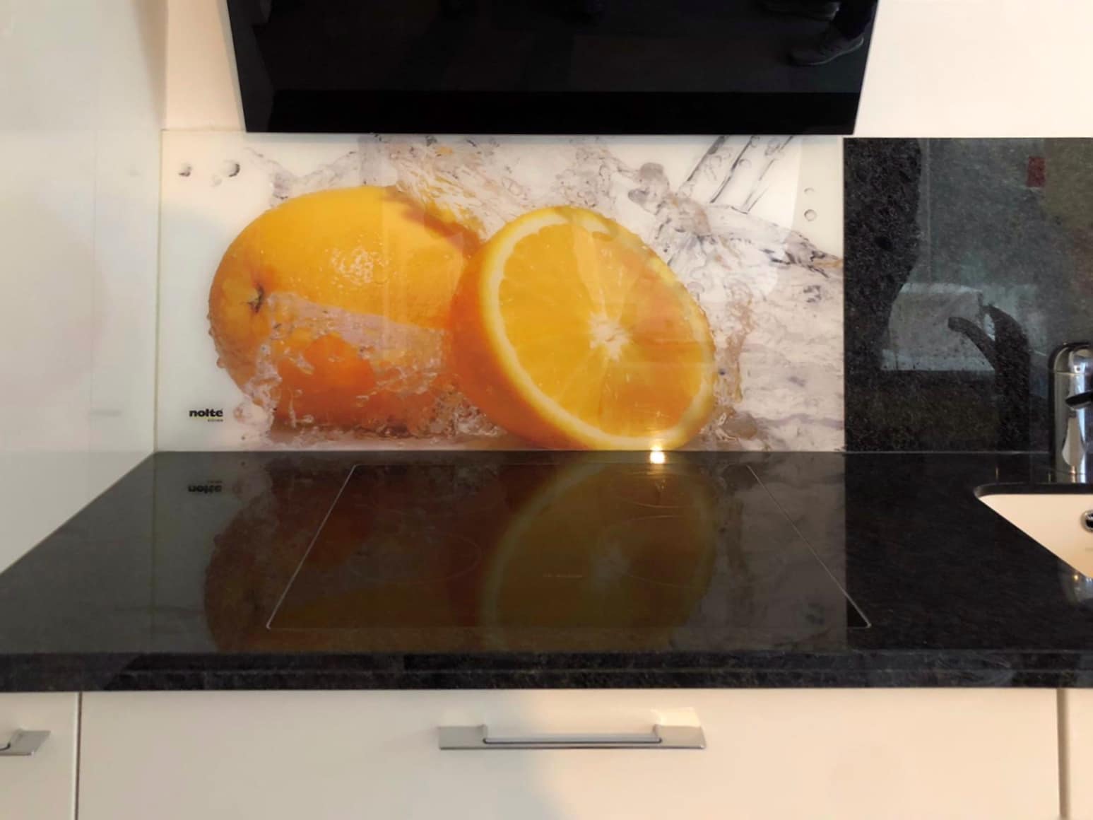 Zwei Orangenscheiben liegen als Dekorplatte vor einer dunklen Arbeitsfläche.