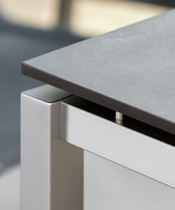 Eine graue HPL-Tischplatte liegt auf einem modernen Tischgestell aus Metall.