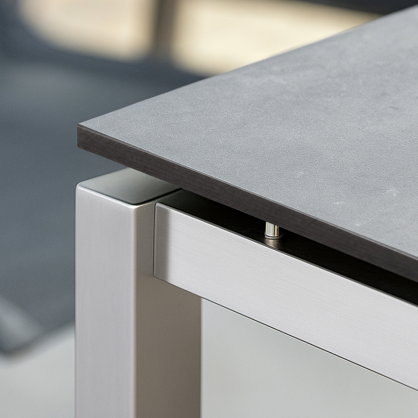 Eine graue HPL-Tischplatte liegt auf einem modernen Tischgestell aus Metall.