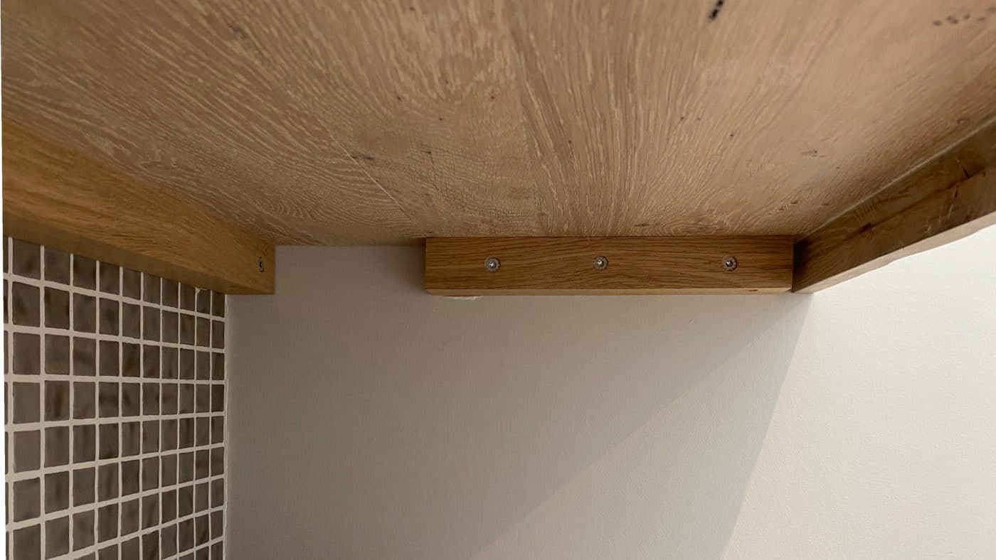 Unter einer massiven Holzfläche ist die stabile Wandhalterung aus Holz klar erkennbar.