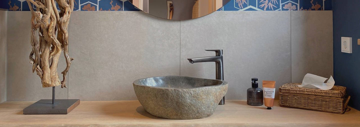 Modernes Badezimmer mit Holzwaschtisch, Steinwaschbecken, runder Spiegelwand und blauer Muster-Tapete.
