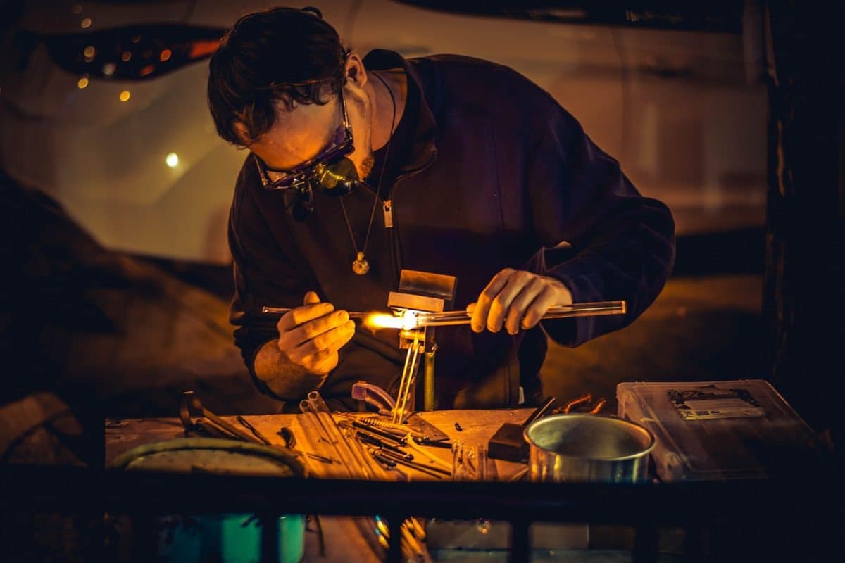 Ein Handwerker formt Glas durch Hitze.