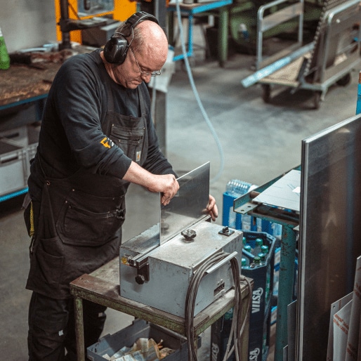Ein Mitarbeiter von zuschnittprofi.mom richtet ein Metallteil sorgfältig an einer Maschine aus.