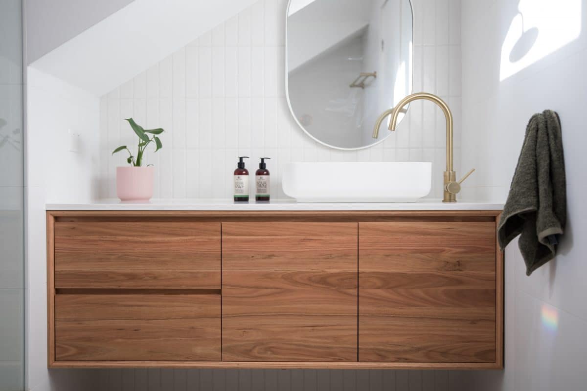 Modernes Badezimmer mit Holzwaschtisch, Aufsatzbecken und goldener Armatur.