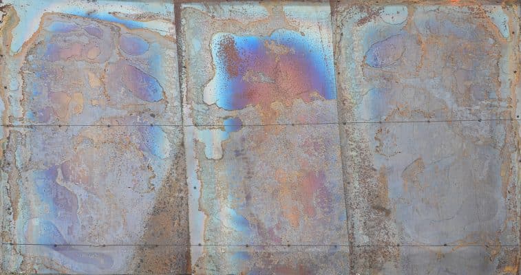 Eine Metalloberfläche weist hitzebedingte Farbverläufe und Anlassfarben auf.