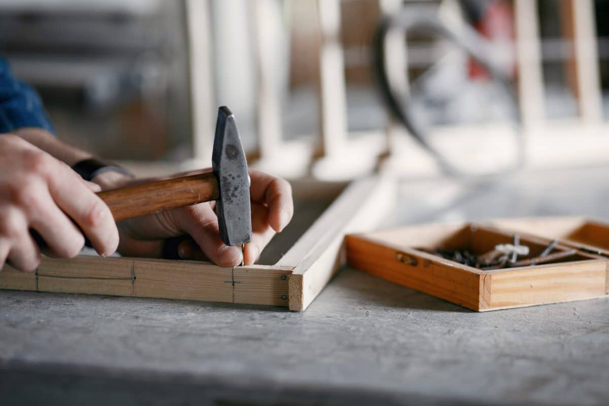 Handwerker bei der Arbeit hämmert Nägel in ein Holzbrett.