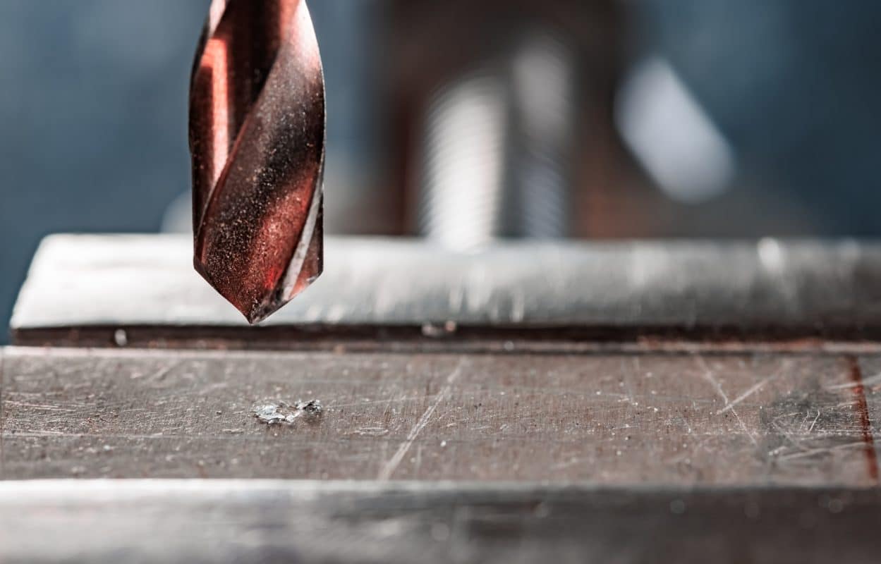 Nahaufnahme eines Bohrers über einer Metalloberfläche im Schraubstock.