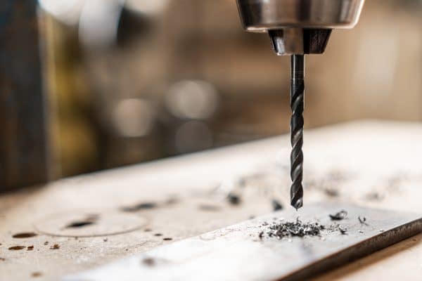 Ein Bohrer durchdringt eine Metallplatte während eines präzisen Arbeitsvorgangs.
