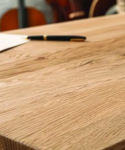 Nahaufnahme eines massiven Eichentisches mit Papier und Stift auf der Oberfläche.