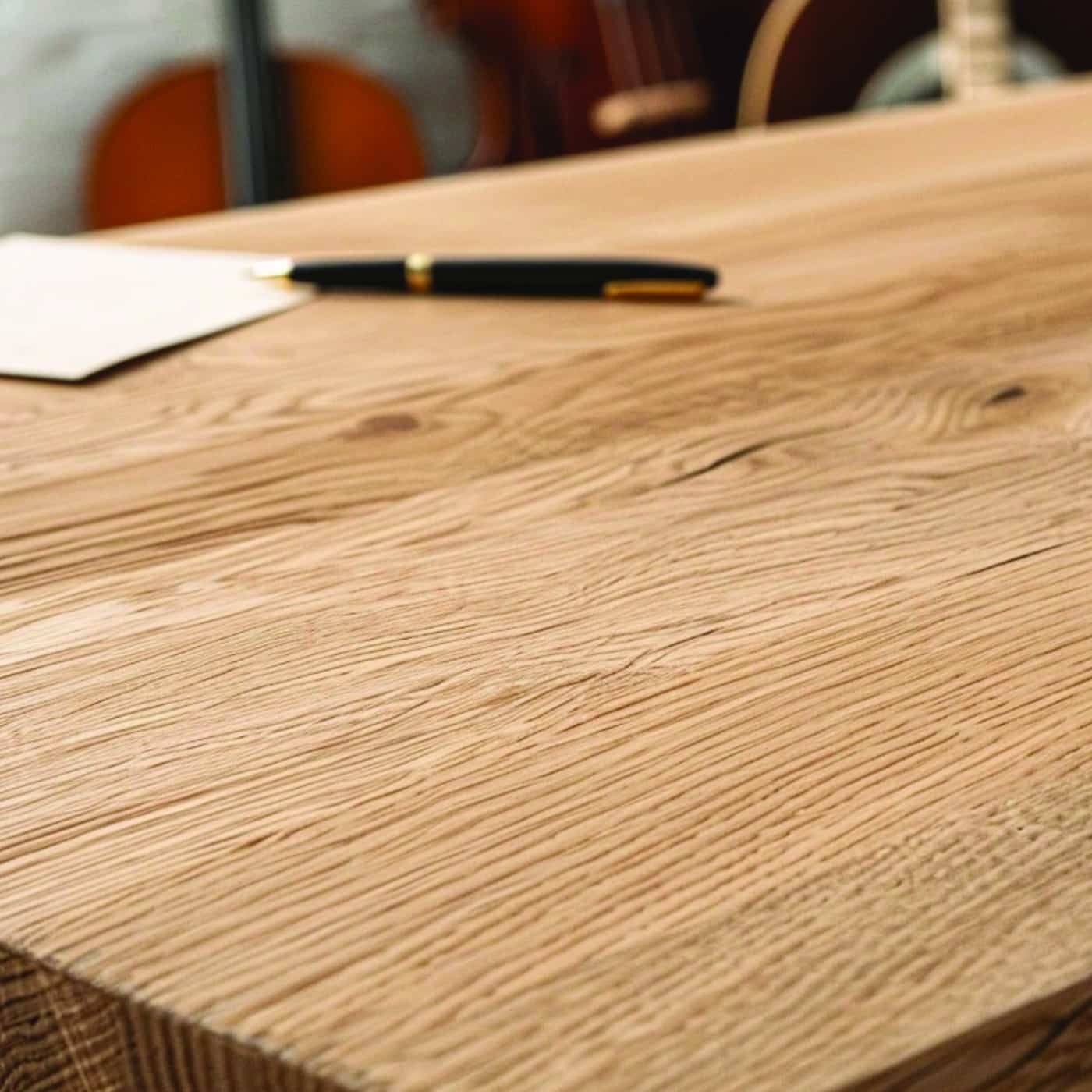 Nahaufnahme eines massiven Eichentisches mit Papier und Stift auf der Oberfläche.
