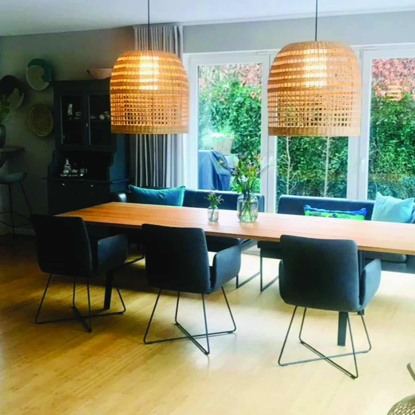 Essbereich mit großem Eichenholztisch, Rattanlampen und modernem, hellen Interieur.