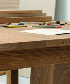Nahaufnahme eines massiven Eichentisches mit Papier, Stiften und Pinseln auf der Oberfläche.