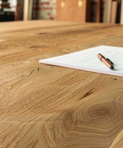 Nahaufnahme eines massiven Eichentisches mit Papier und Stift auf der Oberfläche.