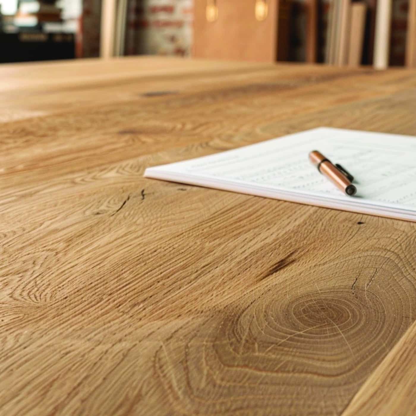 Nahaufnahme eines massiven Eichentisches mit Papier und Stift auf der Oberfläche.