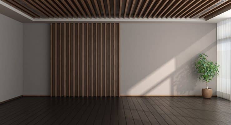 Eine Wand und eine Decke mit vertikalen Holzleisten prägen einen leeren Innenraum mit dunklem Boden.