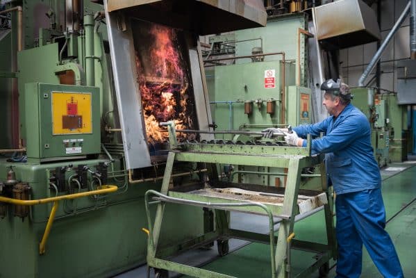 Ein Mitarbeiter bedient eine industrielle Maschine mit glühendem Metall.