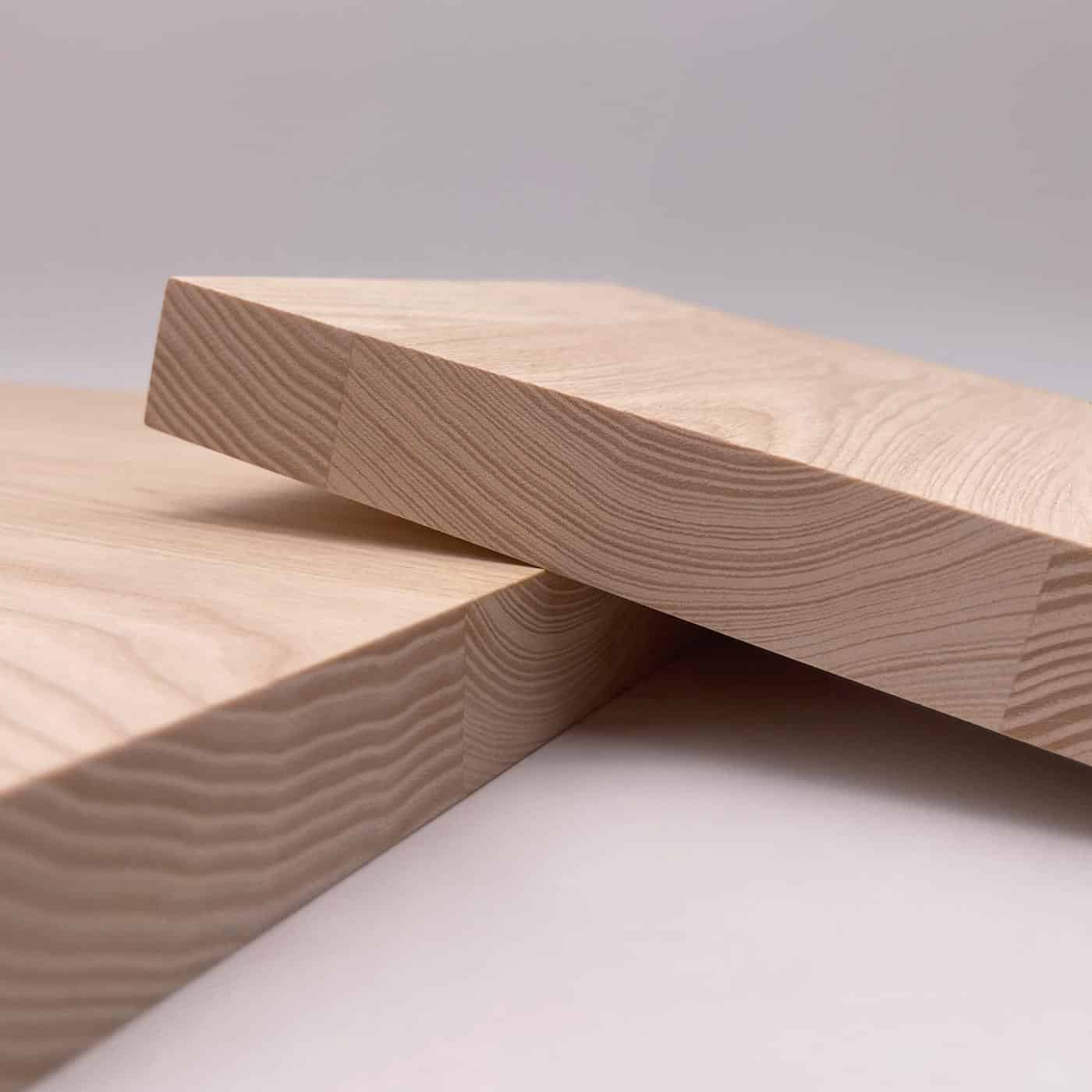 Zwei helle Esche Platten liegen überkreuz auf einer glatten Fläche.