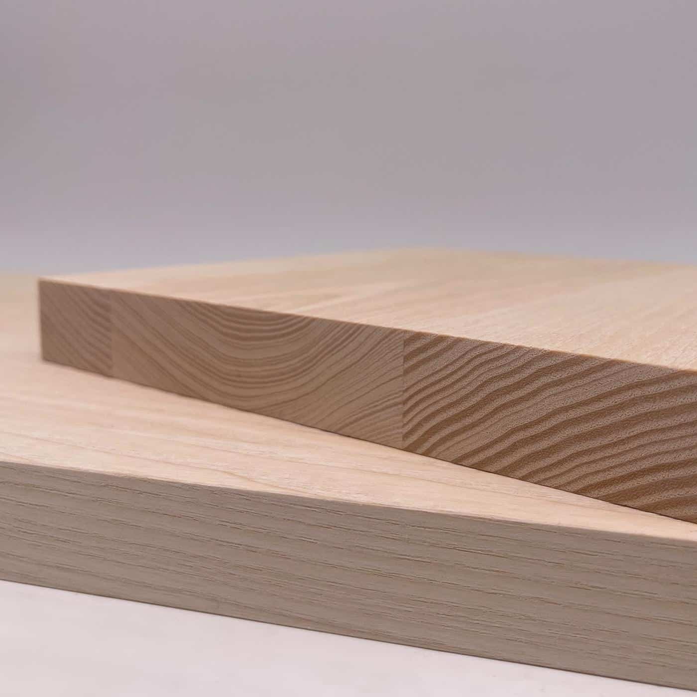 Zwei helle Esche Holzplatten liegen überkreuz auf einer glatten Fläche.