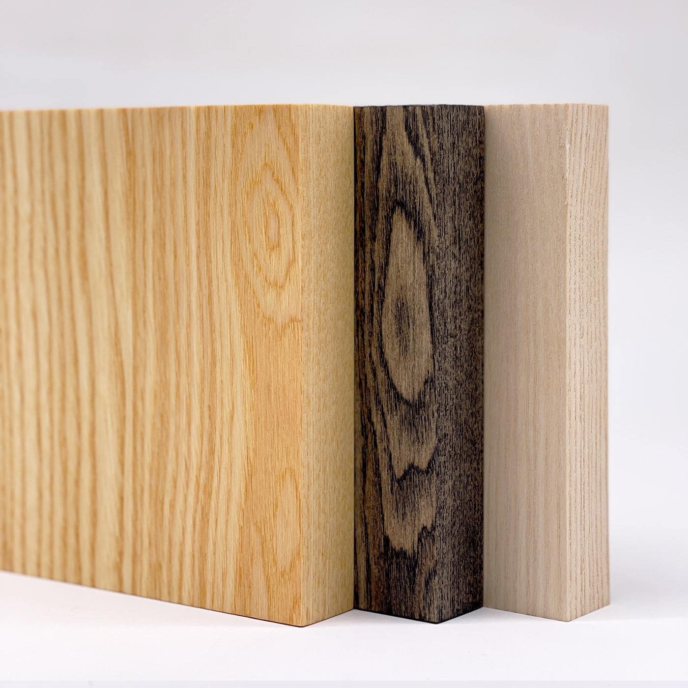 Drei Esche Holzplatten stehen nebeneinander und zeigen verschiedene Farbtöne und Strukturen.