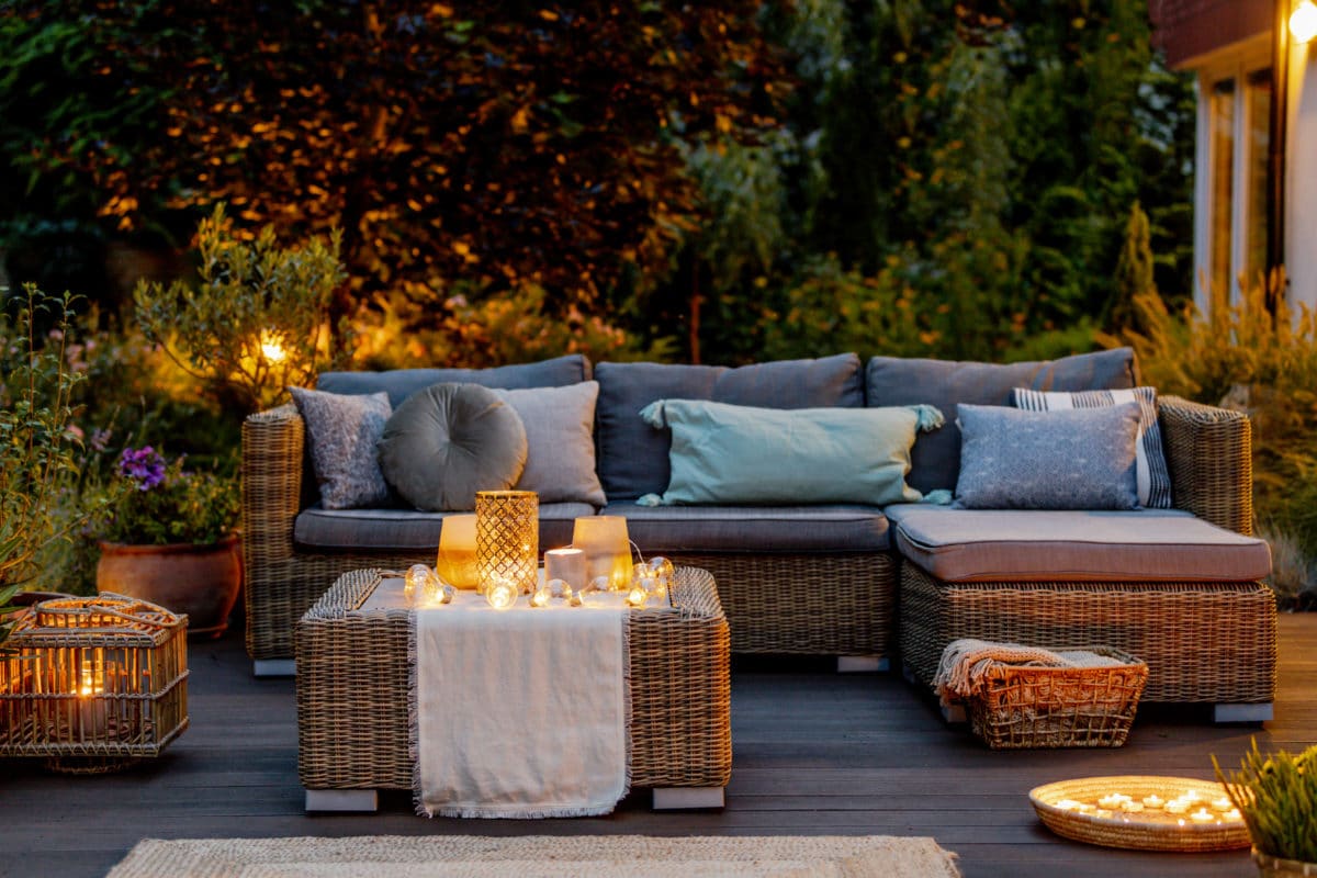 Gemütliche Terrassensitzgruppe mit Rattanmöbeln und Lichterdeko.