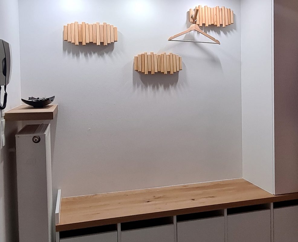 Eine beleuchtete Nische zeigt Holzleisten als Dekoration über einer schlichten Bank.