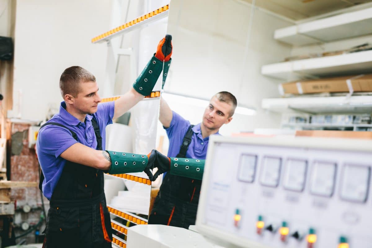 Ein Mitarbeitender prüft ein Bauteil in einer industriellen Fertigungsumgebung.