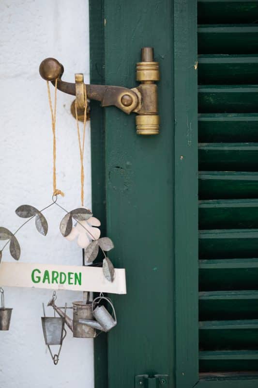 Bronze-Fensterbeschlag an grünem Fensterladen mit Gartendeko.