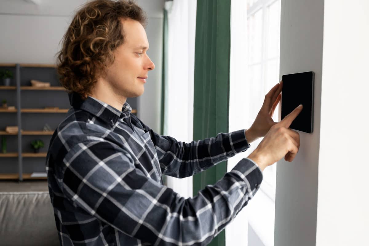 Mann steuert Smart-Home-Funktionen über Wand-Touchpanel.