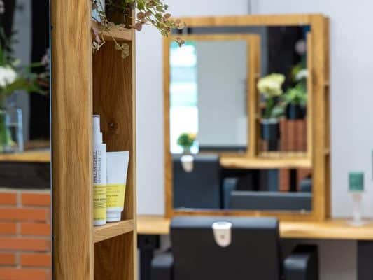 Ein Holzregal steht neben einem Spiegel in einem Friseursalon.
