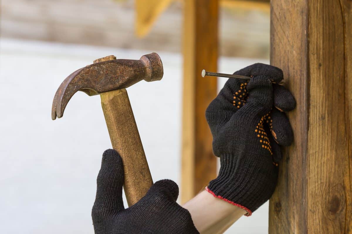 Einsatz eines Hammers beim Einschlagen eines Nagels.