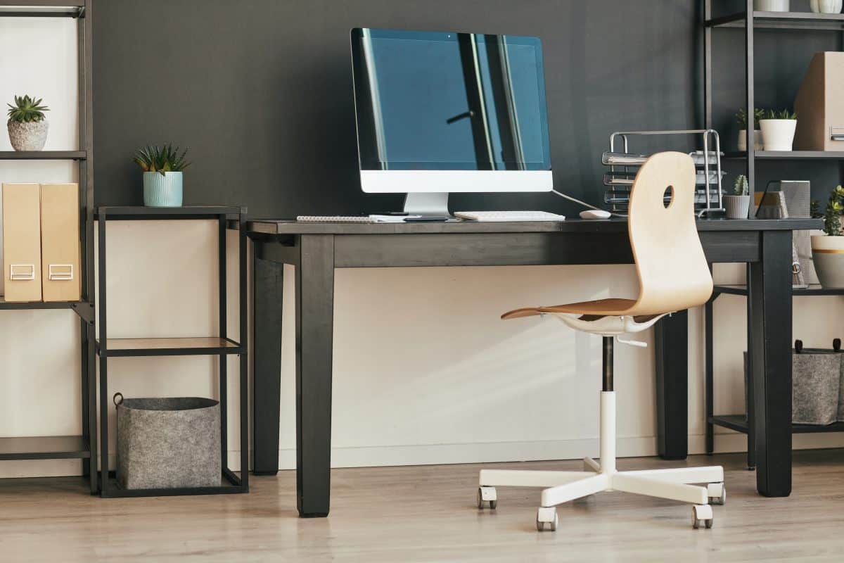 Moderner Arbeitsplatz mit großem Monitor und schwarzem Schreibtisch.