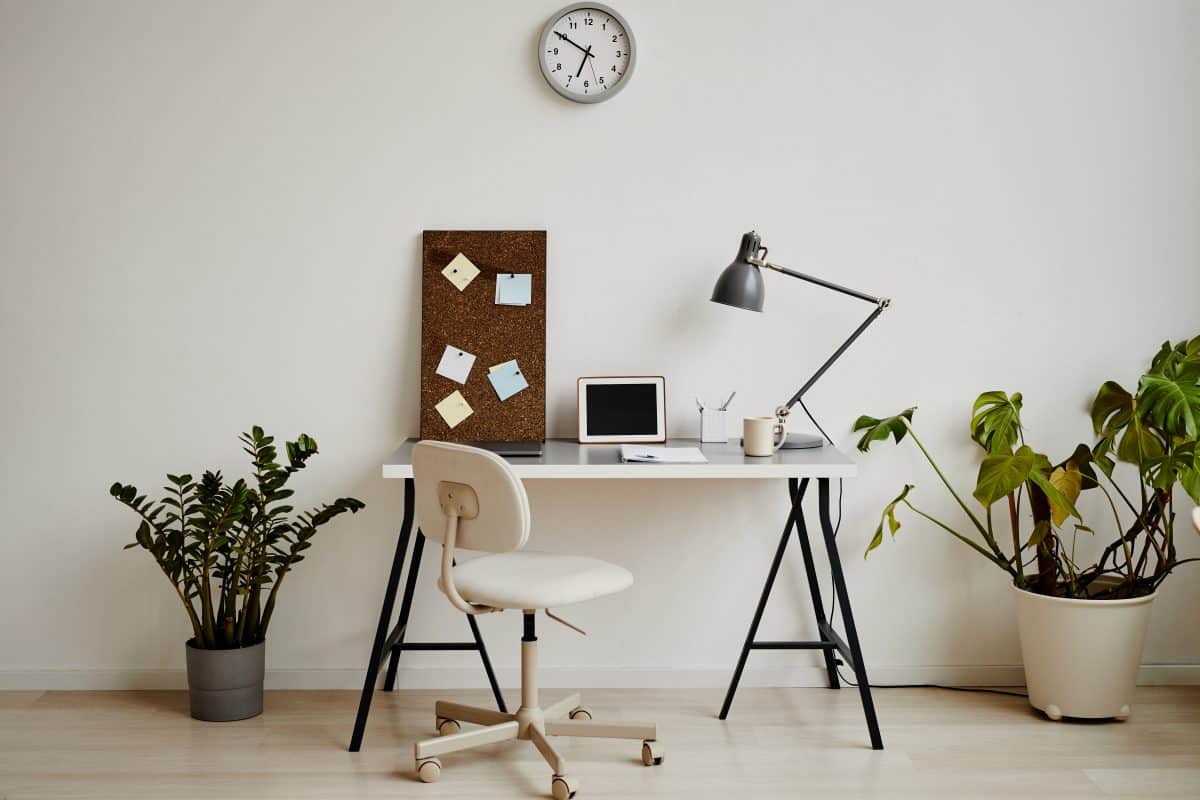 Minimalistischer Schreibtisch mit Pflanzen und Pinnwand im Homeoffice.