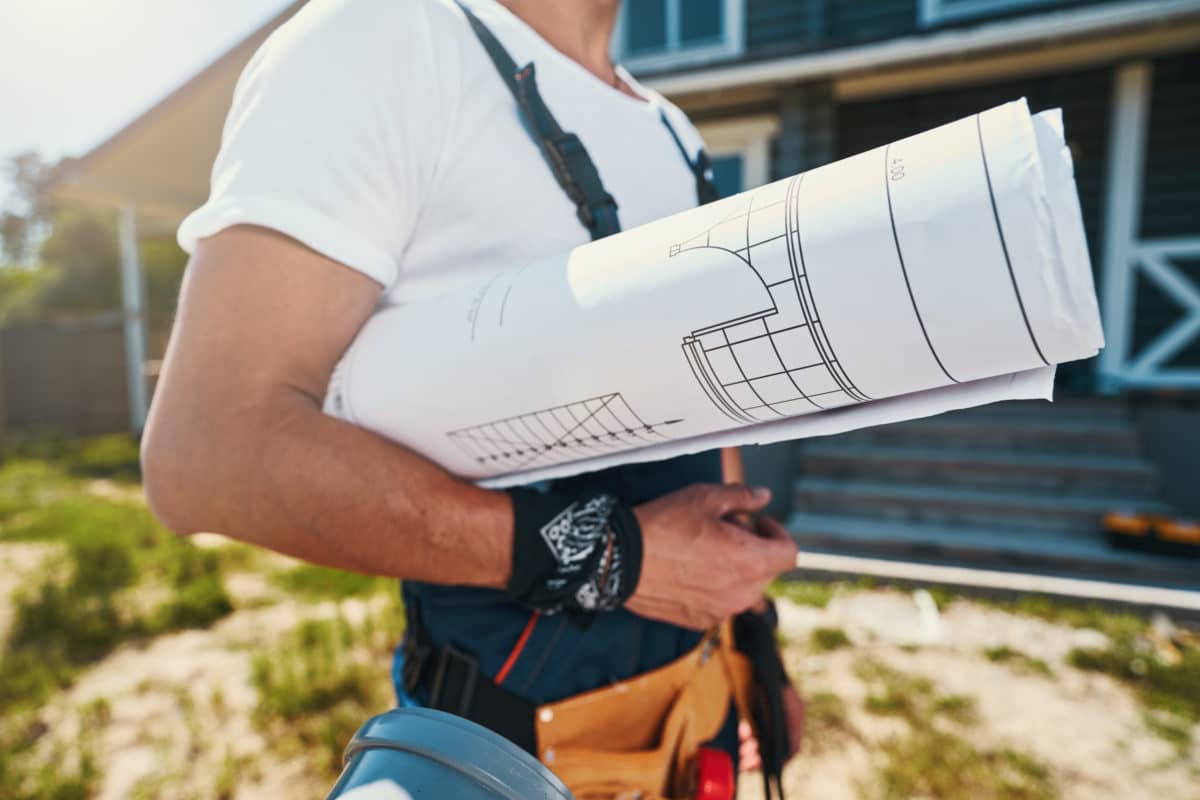 Bebauungsplan gerollt unter dem Arm eines Hausbauers.