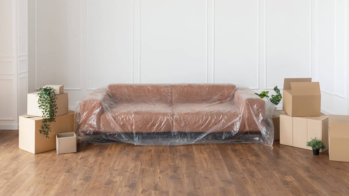 Verlegung und Reparatur Konzept. Modernes stilvolles Sofa mit Plastikfolie bedeckt für Heimdekoration. 