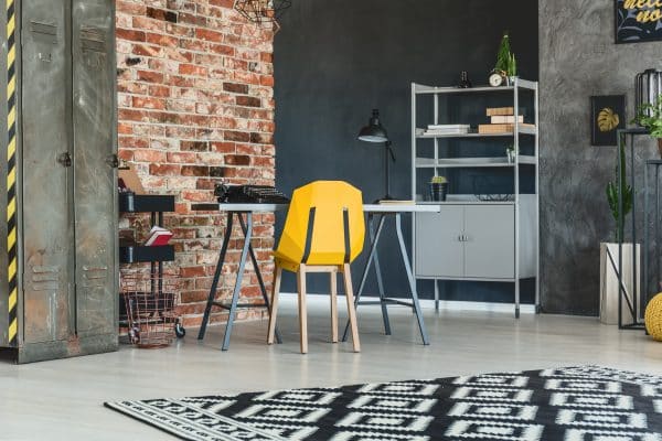 Ein moderner Arbeitsbereich kombiniert Stahlmöbel mit einer Backsteinwand.