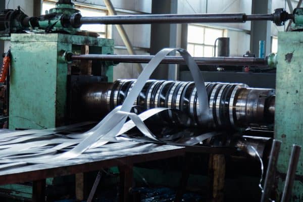 Metallstreifen laufen gebogen durch eine laufende Produktionsanlage.